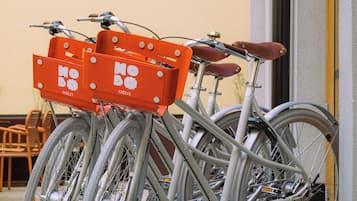 Uma bicicleta com uma caixa de entrega fixada, estacionada em frente a um edifício.