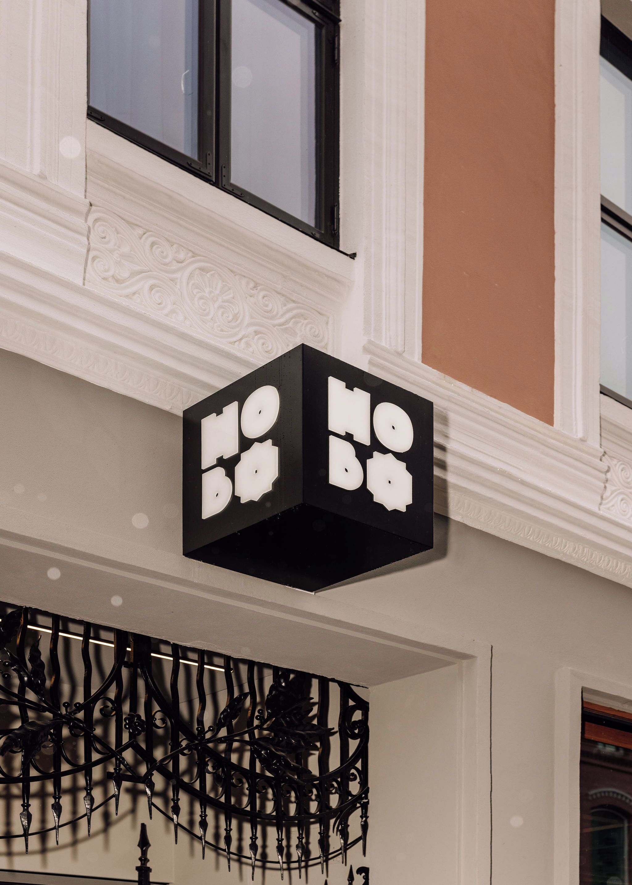 Un letrero negro con letras blancas que indican “NO B&B” sobre una fachada de edificio con molduras decorativas y una ventana arriba.