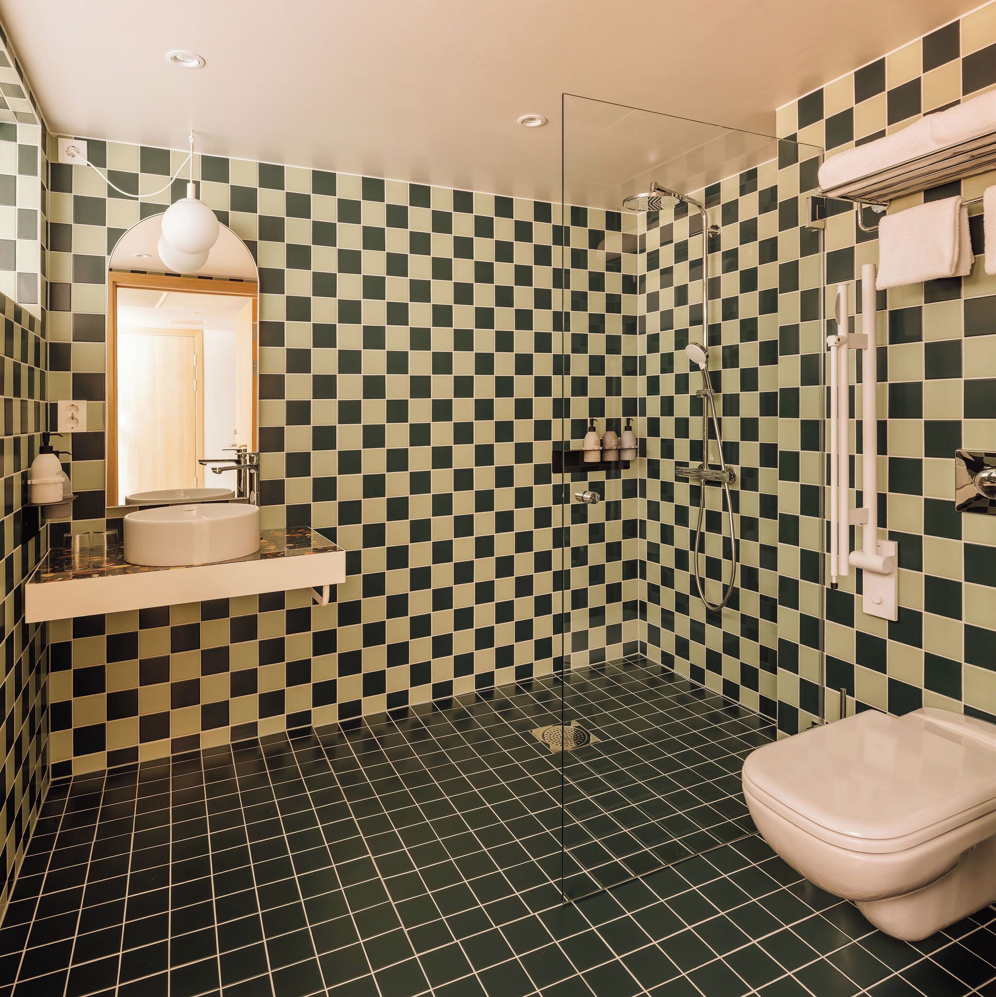 A bathroom with a checkered floor pattern, a sink, a toilet, and a shower area.