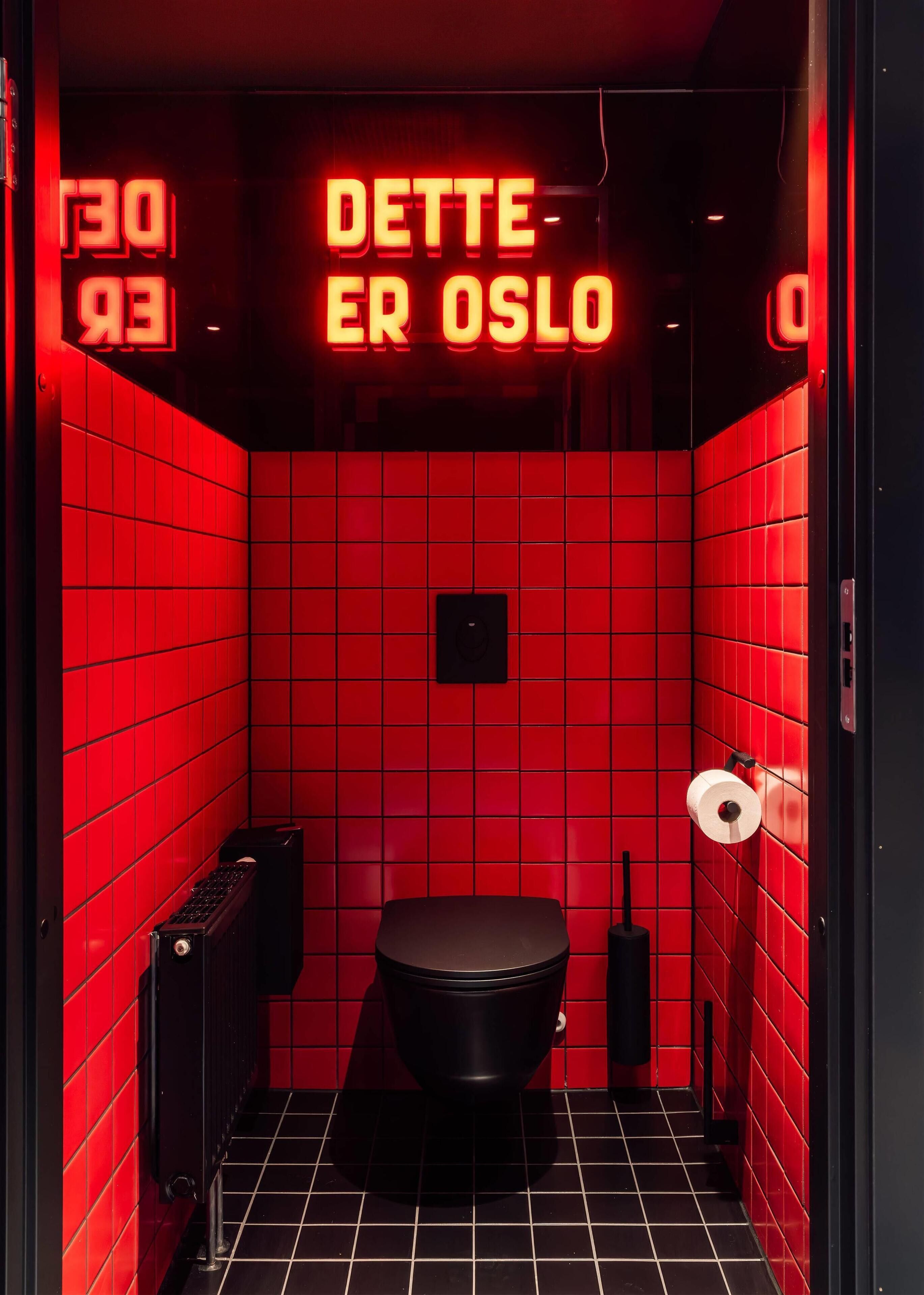 A red-tiled bathroom with a neon sign reading "DETTE ER OSLO" and a black toilet.