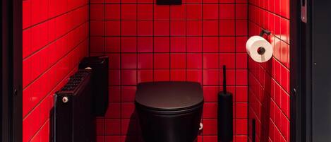 A red-tiled bathroom with a neon sign reading "DETTE ER OSLO" and a black toilet.