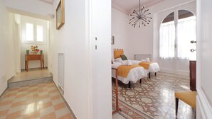 A hotel room with a checkered floor, a bed with a white and orange bedspread, and a patterned rug. - 4bnb - Monteverde Chic Comfort (Rome)