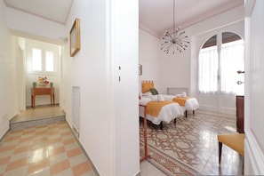 A hotel room with a checkered floor, a bed with a white and orange bedspread, and a patterned rug. - 4bnb - Monteverde Chic Comfort (Rome)