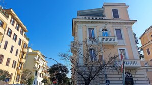 A multi-story building with balconies, a clear blue sky, and a sign with the number 936. - 4bnb - Monteverde Chic Comfort (Rome)