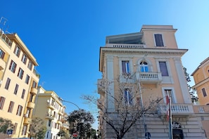 A multi-story building with balconies, a clear blue sky, and a sign with the number 936. - 4bnb - Monteverde Chic Comfort (Rome)