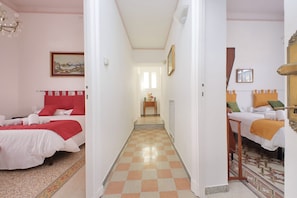 A hotel room with a checkered floor, a bed with a red headboard, and a bedside table with a lamp. - 4bnb - Monteverde Chic Comfort (Rome)