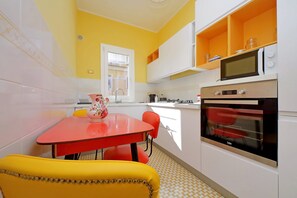 A kitchen with a red table, yellow chairs, a microwave, and an oven. - 4bnb - Monteverde Chic Comfort (Rome)