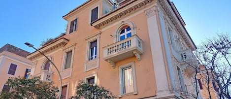 A multi-story building with classical architecture, featuring arched windows, balconies, and decorative moldings.