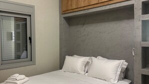 Une chambre à coucher avec un lit, des oreillers, une fenêtre et une armoire en bois.