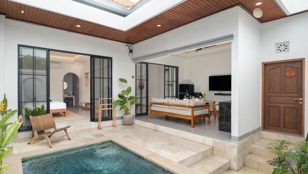 En rummelig opholdsstue med swimmingpool, sofa, spisebord og fjernsyn.
