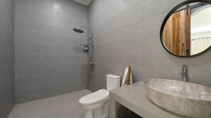 A modern bathroom with a shower, toilet, and a large sink with a marble basin. - Villa Kamila 2 by Villa Finder  (Seminyak)
