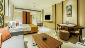Ein modernes Hotelzimmer mit Bett, Sofa, Esstisch und Fernseher.