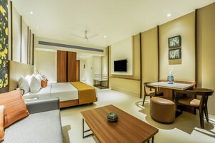 Una habitación de hotel moderna con cama, sofá, mesa de comedor y televisor.