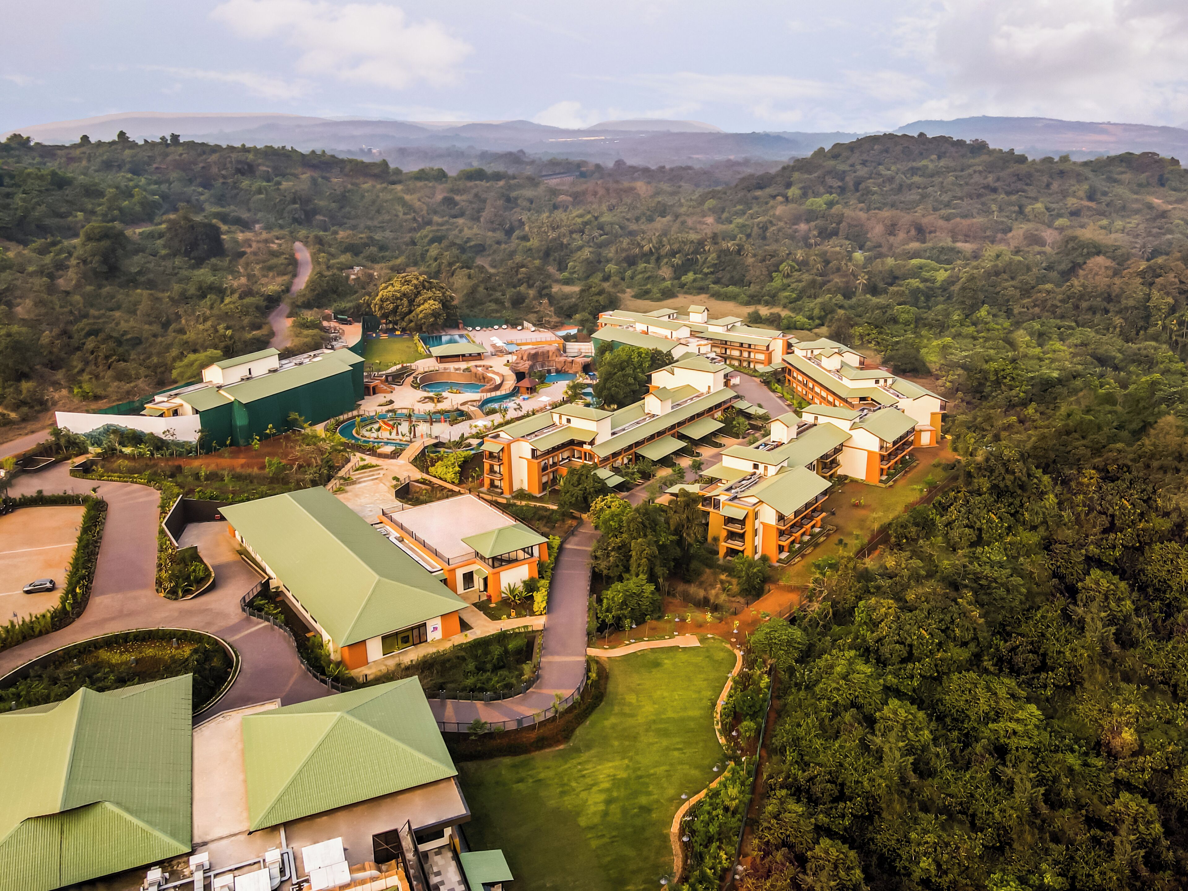 An aerial view of a resort with multiple buildings, a swimming pool, and a well-maintained lawn.