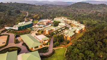 An aerial view of a resort with multiple buildings, a swimming pool, and a well-maintained lawn.