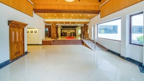 A spacious lobby with a high ceiling, wooden beams, a chandelier, and a staircase leading to an upper level. - Club Mahindra Le Vintuna (Gangtok)