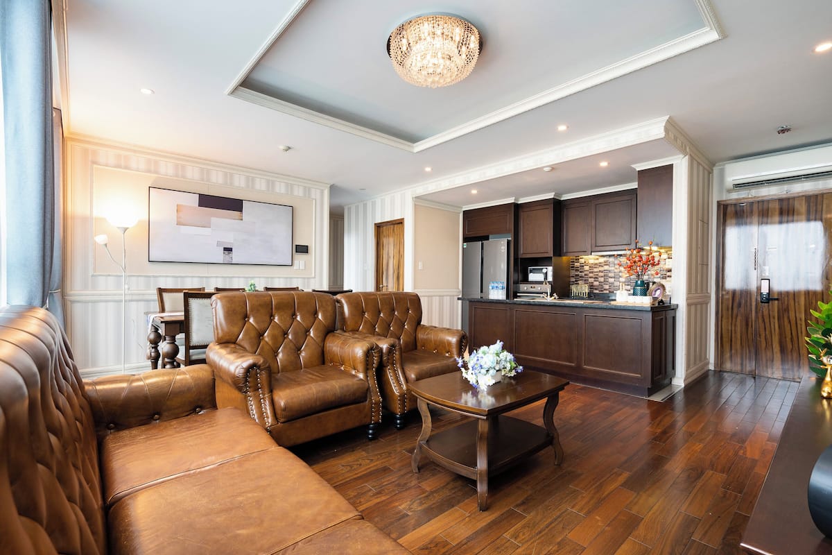 Ein geräumiges Wohnzimmer mit einer Ledersofa, einem Holztisch und einer Chandelier.