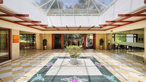 A spacious lobby with a checkered floor, a central potted plant, and a glass ceiling. - Club Mahindra Golden Landmark (Mysore)