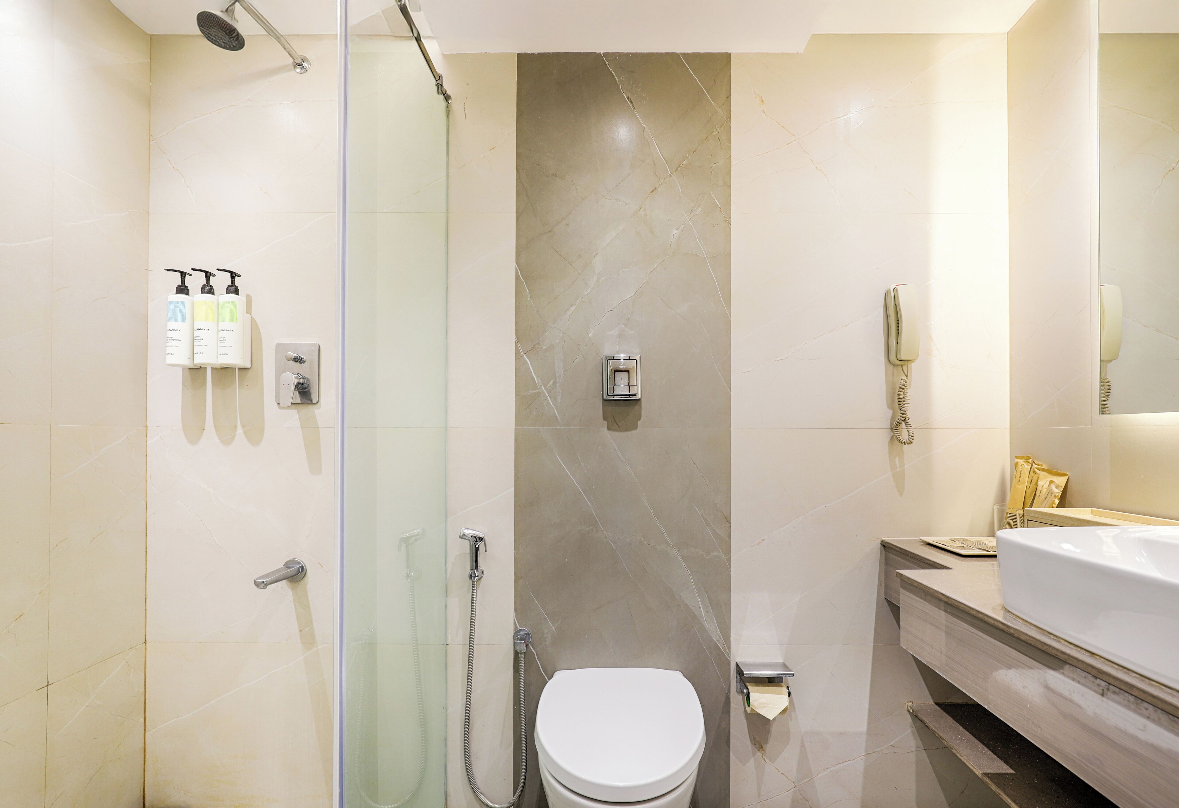 A modern bathroom with a glass-enclosed shower, a white toilet, and a vanity with a mirror.