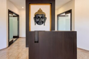 A reception desk with a framed Buddha head sculpture above it.