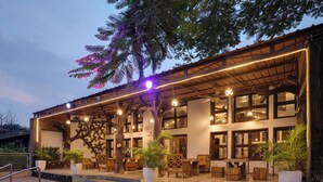 A restaurant with outdoor seating, a pool, and a tree mural. - Club Mahindra Netrang (Netrang)