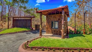 A rustic wooden cabin with a red roof, surrounded by a well-maintained garden and a gravel driveway. - Club Mahindra Netrang (Netrang)