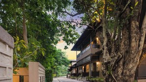 A tree-lined street with a modern building featuring balconies and a brick pathway. - Club Mahindra Netrang (Netrang)