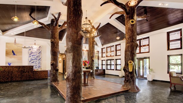 A spacious lobby with a unique tree-themed reception area, large windows, and a modern chandelier. - Club Mahindra Netrang (Netrang)