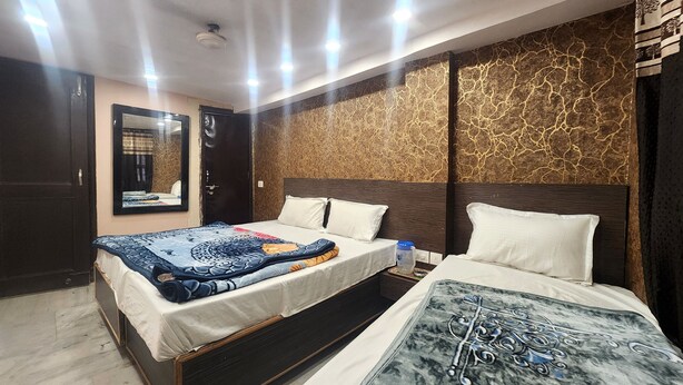 Ett hotellrum med en stor säng, en mindre säng, en spegel och en vägg med ett mönster.
