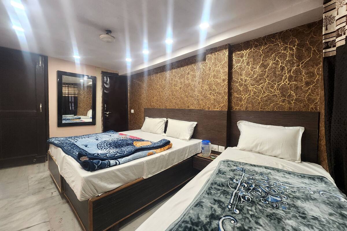 Ein Hotelzimmer mit einem großen Bett, einem kleineren Bett, einem Spiegel und einer Wand mit Muster.