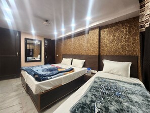 A hotel room with a large bed, a smaller bed, a mirror, and a patterned wall. - Hotel The Divine (New Delhi)