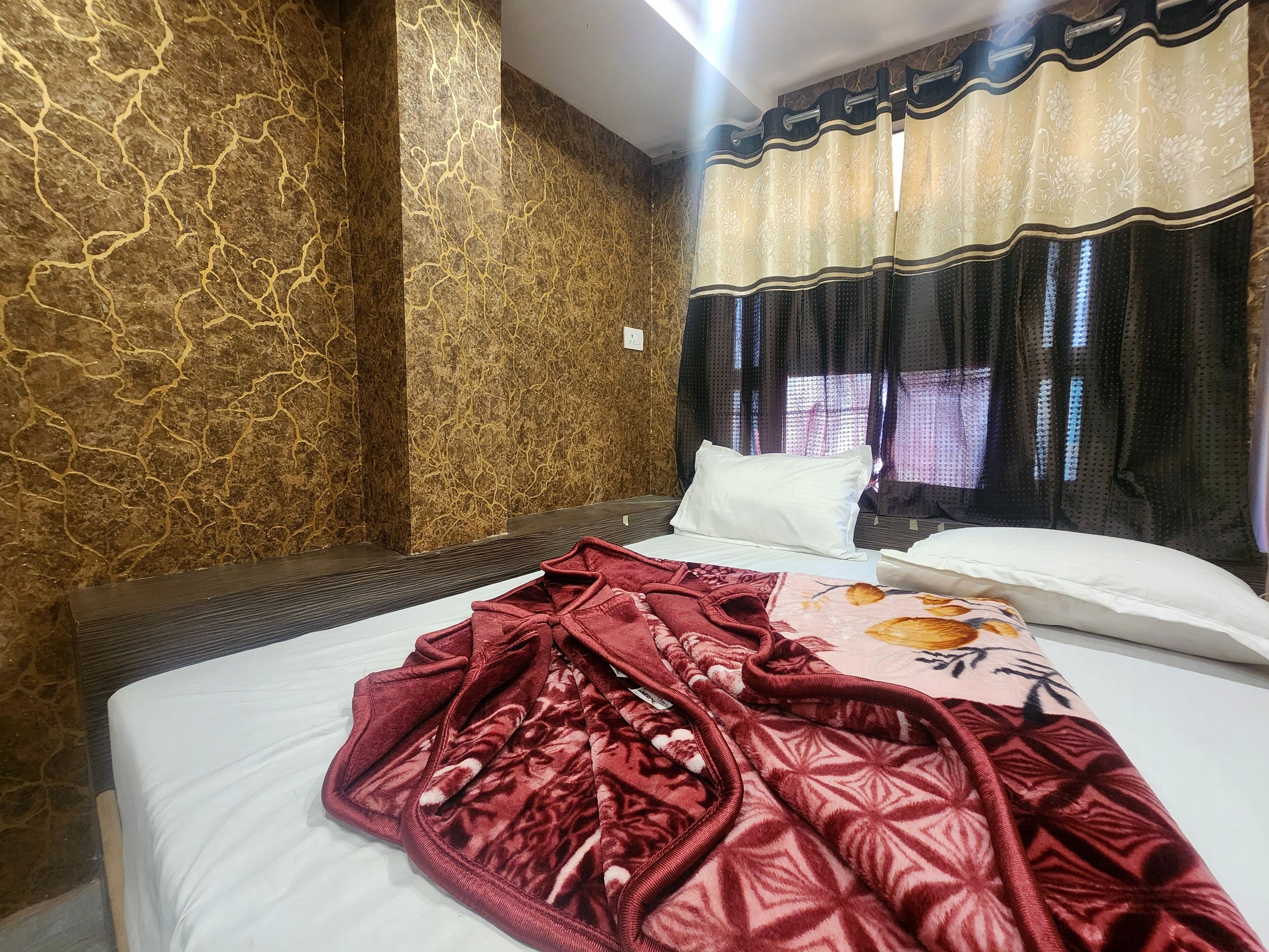 Ein Hotelzimmer mit einem Bett, einer roten Decke und einem gemusterten Kopfkissen.