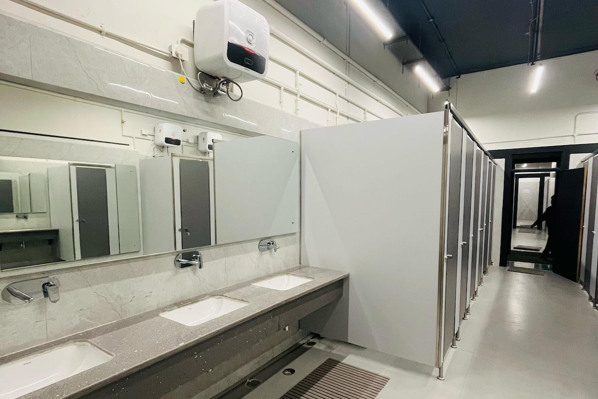 A modern restroom with two sinks, a hand dryer, and a ventilation system.
