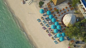 An aerial view of a beach with rows of sun loungers and umbrellas, a large thatched structure, and a pool area. - Living Asia Sunset Resort (Gili Air)