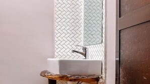 Une salle de bain avec un lavabo blanc, un meuble en bois et un miroir au-dessus.