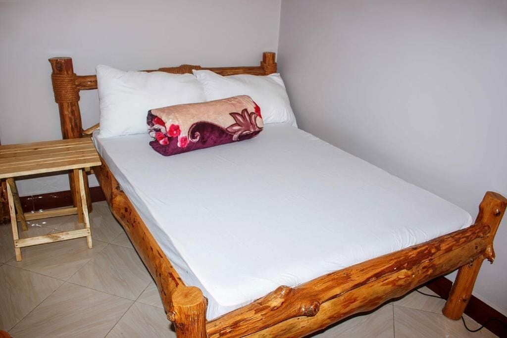 Een houten bed met wit beddengoed en een decoratief kussen.