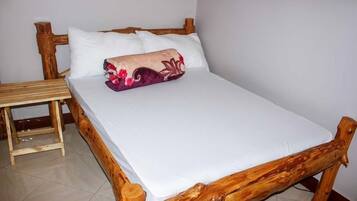Un lit en bois avec une literie blanche et un coussin décoratif.