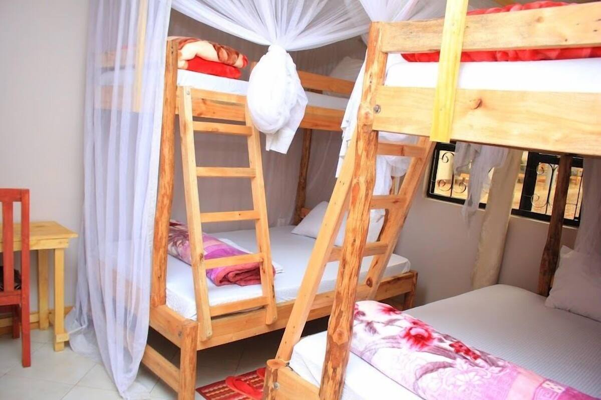 A bunk bed room with a ladder, a small table, and a chair.