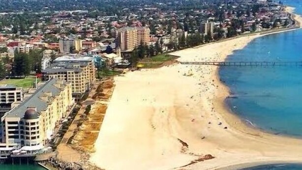 An aerial view of a coastal area with a sandy beach, a pier, and a row of buildings along the shore. - Woodville Garden Home in great location (Woodville Gardens)