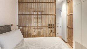 Un dormitorio moderno con cama, un separador de madera y un armario.