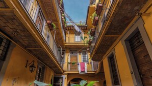 Un callejón estrecho con edificios amarillos, balcones con plantas y ropa tendida.