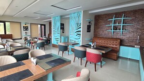 A modern dining area with glass tables, cushioned chairs, and a brick accent wall. - Cozy Kanatal Hotel And Resort (Tehri)
