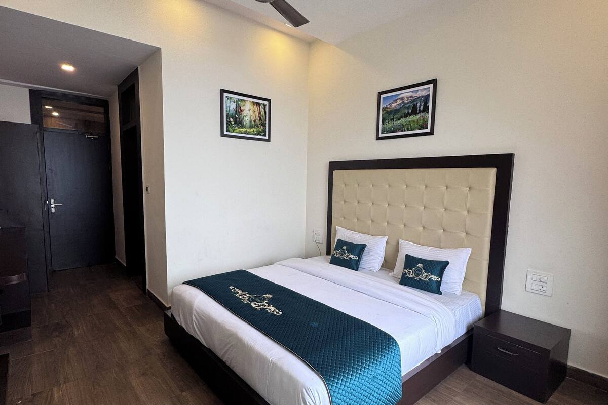 Ein Hotelzimmer mit einem Bett, einem Deckenventilator und zwei gerahmten Bildern an der Wand.