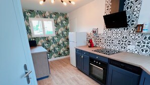 A modern kitchen with a built-in oven, dishwasher, and microwave. There is a window with a view of greenery outside.