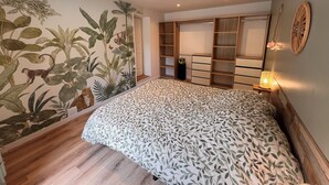 A bedroom with a large bed, a wardrobe, and a wall with a nature-themed mural.