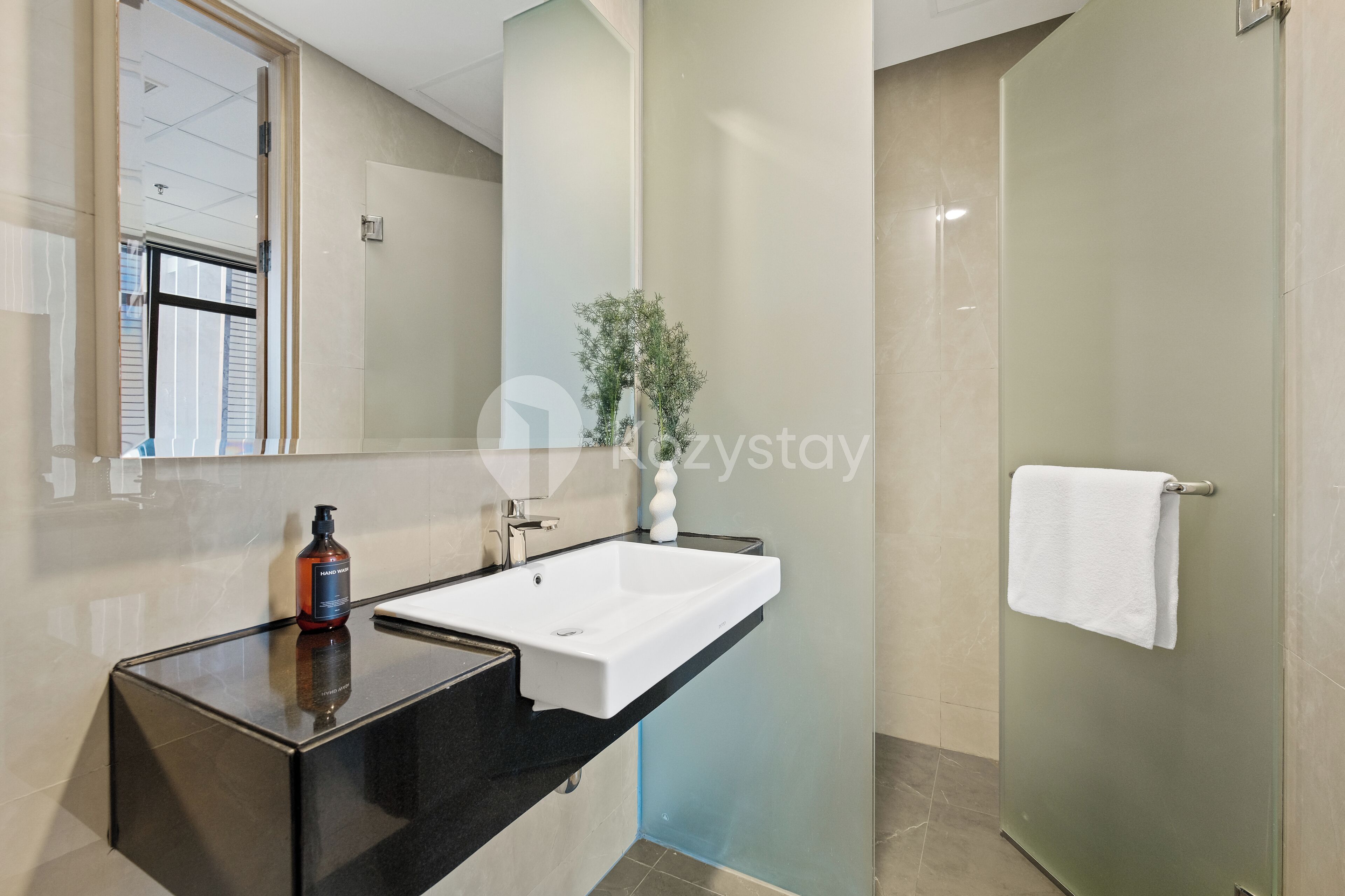 A modern bathroom with a black countertop, white sink, and a glass shower enclosure.