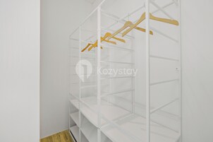 Μια λευκή ντουλάπα με ξύλινες κρεμάστρες και άδεια ράφια.