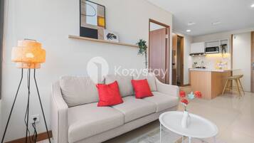A modern living room with a sofa, a coffee table, and a kitchen area in the background.