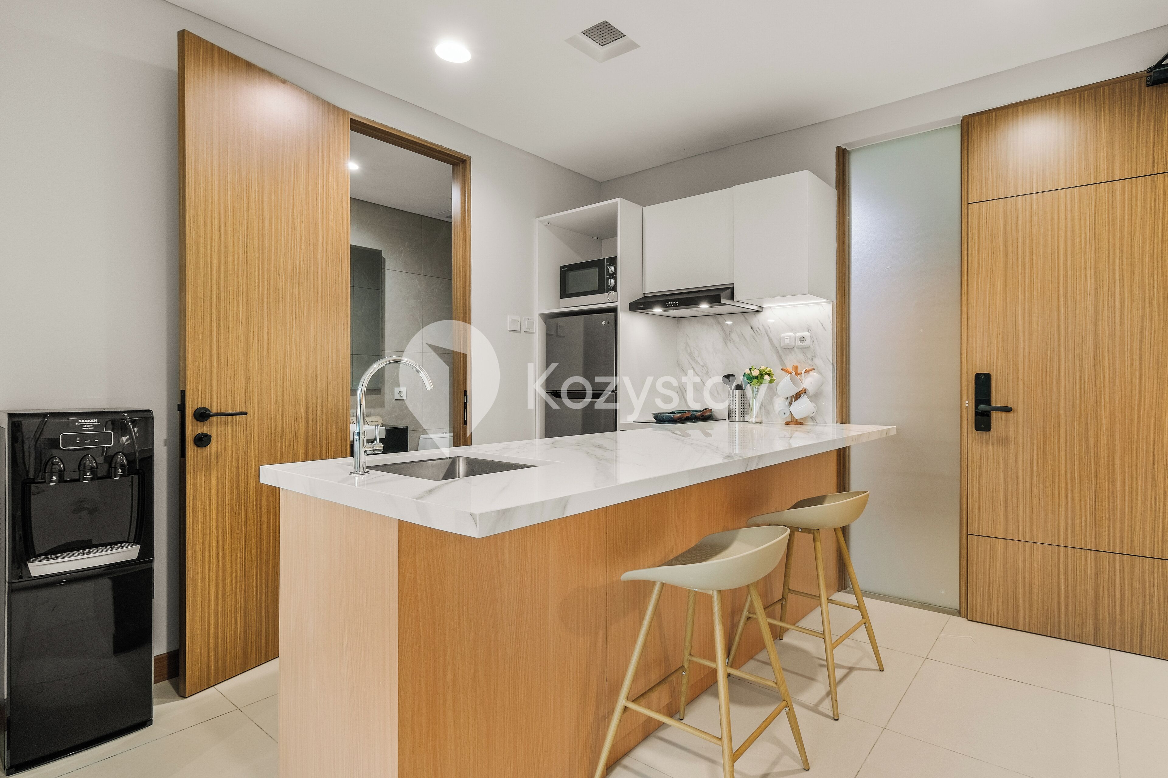 A modern kitchen with a central island, wooden cabinets, a built-in microwave, and a refrigerator.
