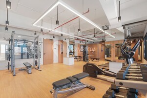 Et moderne fitnesscenter med forskellig træningsudstyr, trægulv og et lyst, veloplyst interiør.